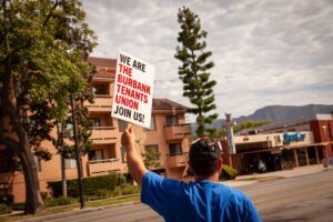 Man with a cap holding a sign "We are the Burbank Tenants Union"
